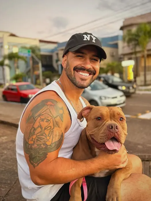Vinícius Belotti, adestrador da BeDog, abraçado a um cão